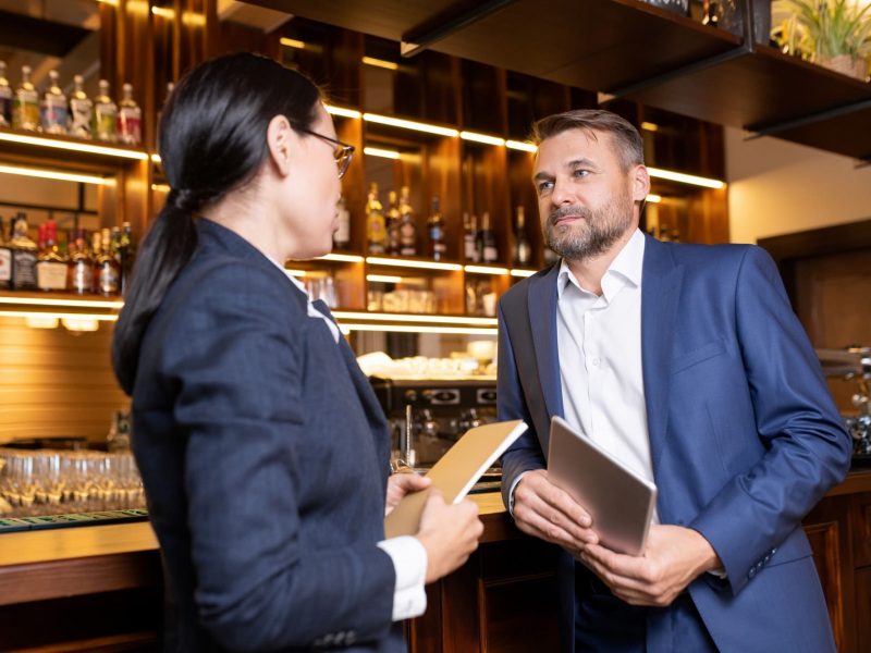 Two owners of luxurious restaurant interacting by bar counter